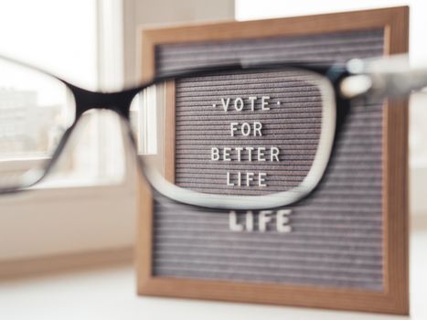 Letter board with words Vote for Better Life. Announcement of USA Presidential Election at 3rd November 2020. Call to go to the vote. Closer view on letter board through eyeglasses.