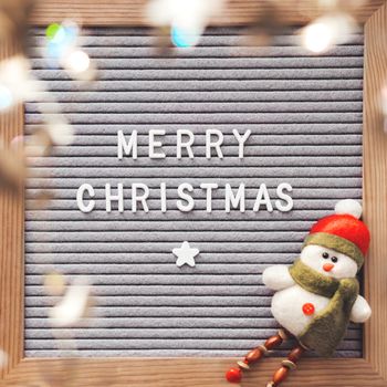 Letter board with season greeting Merry Christmas. Winter holiday spirit. Decorative snowman and shiny tinsel with stars.