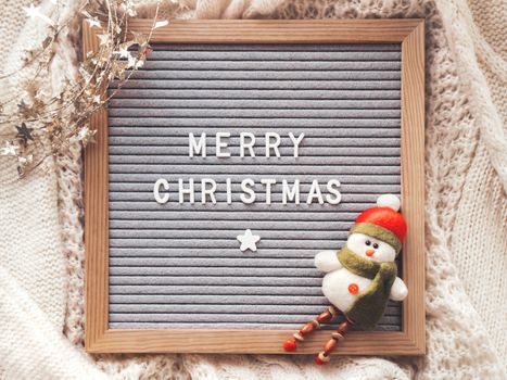 Letter board with season greeting Merry Christmas. Winter holiday spirit. Decorative snowman and shiny tinsel with stars.