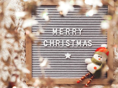 Letter board with season greeting Merry Christmas. Winter holiday spirit. Decorative snowman and shiny tinsel with stars.