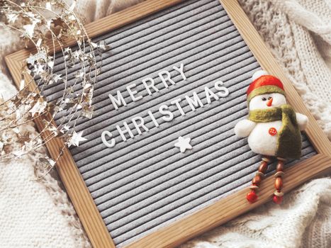 Letter board with season greeting Merry Christmas. Winter holiday spirit. Decorative snowman and shiny tinsel with stars.