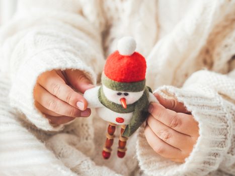 Kid with felt decorative snowman for Christmas tree. Boy in cable-knit oversized sweater. Cozy outfit for snuggle weather. Funny character with red Santa Claus hat. Winter holiday spirit. New year.