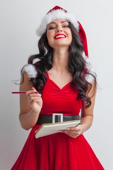 Pretty smiling pin-up Santa girl with wish list letter and red pencil