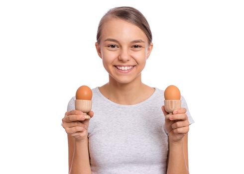 Portrait of beautiful young teen girl, holding boiled egg and spoon for breakfast, isolated on white background