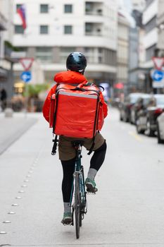 Unrecognizable courier on bicycle delivering food in cCity. Empty streets during shelter in place times during corona virus pandemic, 2020.