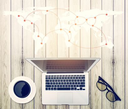 Top view of modern working  business office desk - notebook or laptop with connection worldmap network on wood table texture background, communication concept.