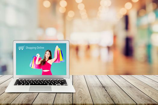 shopping online with labtop, notebook on table top and bokeh background, computer with beautiful asian woman holding shopping bag and smile present on display.