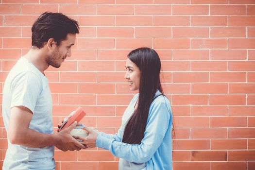 Asian couple young man giving gift box to woman outdoors,  relationship with celebration birthday of boyfriend and girlfriend with happy.