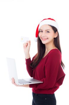 Portrait of beautiful asian young woman in santa hat using laptop computer and holding credit card isolated on a white background, shopping holiday concept.