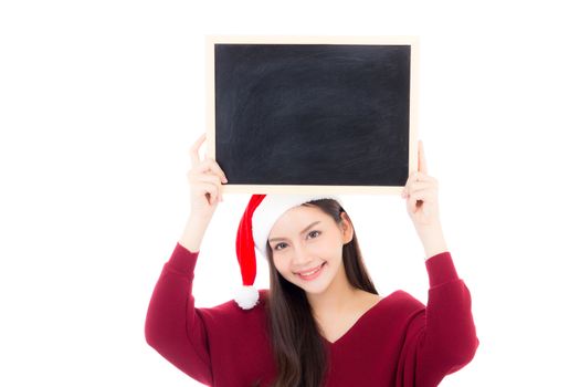 Portrait of beautiful christmas asian young woman in santa hat holding chalkboard with copyspace empty isolated on white background, xmas holiday concept.