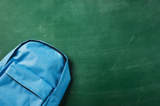 Top view flat lay of blue school bag backpack at a green chalkboard and have copy space for your text, Back to school education concept