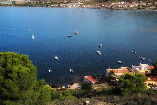 La Azohia, Cartagena, Murcia, Spain- October 2, 2019: Beautiful beach with boats , cliffs and mountains in La Azohia village in Cartagena, Murcia, Spain in a sunny day. Views from Santa Elena tower viewpoint.