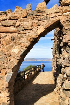 La Azohia, Cartagena, Spain- October 2, 2019: Tourist visiting and relaxing in Santa Elena tower in a sunny day of Autumn. Strong stone arch of Santa Elena tower in the foreground.