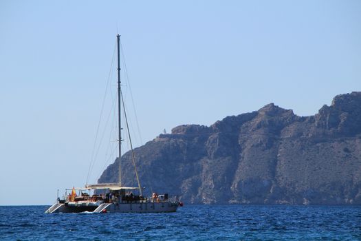Mazarron, Murcia- October 2, 2019: Tourist catamaran full of tourists furrowing the coast in a sunny and clear day in Mazarron