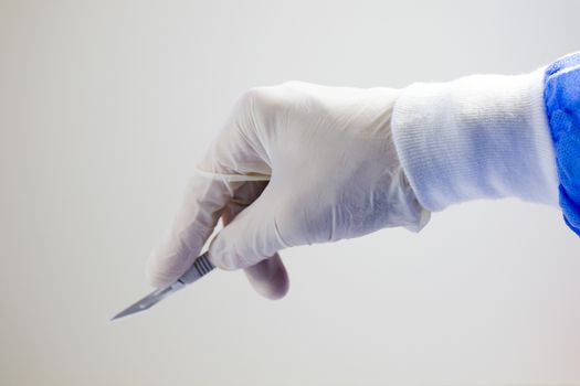 Surgery knife holding on the white background, studio shot. Operation equipment.