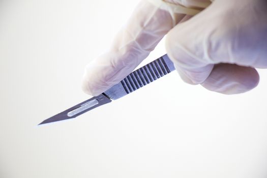 Surgery knife holding on the white background, studio shot. Operation equipment.