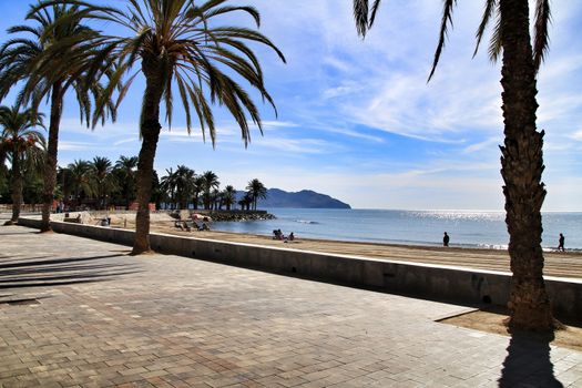 Mazarron, Murcia, Spain- October 3, 2019: Beautiful beach view from the promenade in a sunny and clear day in Mazarron, Murcia, Spain. People relaxing and sunbathing on the beach.