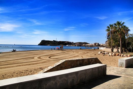 Mazarron, Murcia, Spain- October 3, 2019: Beautiful beach view from the promenade in a sunny and clear day in Mazarron, Murcia, Spain. People relaxing and sunbathing on the beach.