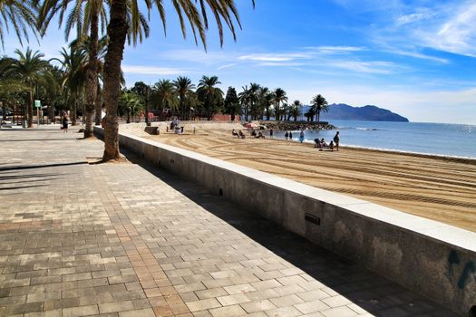 Mazarron, Murcia, Spain- October 3, 2019: Beautiful beach view from the promenade in a sunny and clear day in Mazarron, Murcia, Spain. People relaxing and sunbathing on the beach.