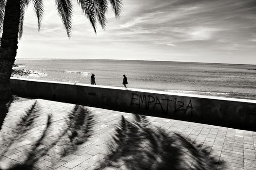 Mazarron, Murcia, Spain- October 3, 2019: Beautiful beach view from the promenade in a sunny and clear day in Mazarron, Murcia, Spain. Empathic word written on the wall.