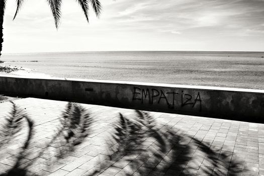 Mazarron, Murcia, Spain- October 3, 2019: Beautiful beach view from the promenade in a sunny and clear day in Mazarron, Murcia, Spain. Empathic word written on the wall.