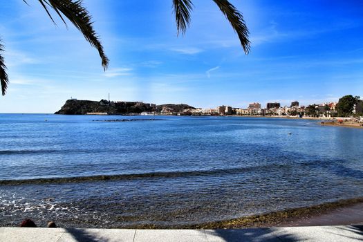 Mazarron, Murcia, Spain- October 3, 2019: Beautiful beach view from the promenade in a sunny and clear day in Mazarron, Murcia, Spain. People relaxing and sunbathing on the beach.