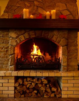 Warm cozy fireplace with real wood burning in it. Cozy winter concept. Christmas and travel background with space for your text