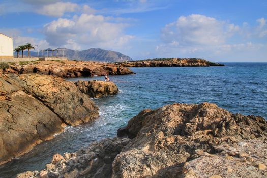 Isla Plana, Murcia, Spain- October 2, 2019: Fisherman and his wife fishing on the rocks in the evening on Isla Plana beach in a sunny day. Cartagena province, Murcia,Spain.