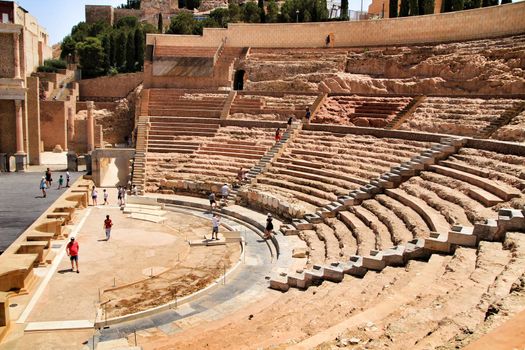 Cartagena, Murcia, Spain- July 25, 2019: Tourists visiting Archeological remains of the roman amphitheater of Cartagena in a sunny day of summer.