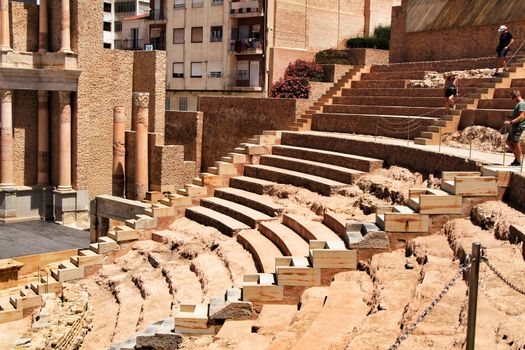 Cartagena, Murcia, Spain- July 25, 2019: Tourists visiting Archeological remains of the roman amphitheater of Cartagena in a sunny day of summer.