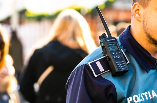 Police officer holding walkie talkie on his shoulder during intervention in Bucharest, Romania, 2020