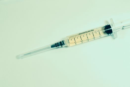 Medical needle on the sterile table with liquid vaccine, yellow vaccine for viruses. Vaccination and antibiotics. Studio shoot.