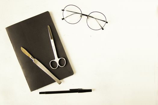 Medical, anatomy, veterinary, biology students stainless steel and notebook with glass and pencil on the white background. Studio shoot.