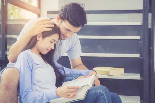 Couple asian handsome man and beautiful woman reading book and smile at home, boyfriend and girlfriend with activities together for leisure, education concept.