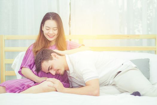 Beautiful pregnant asian woman and husband listening to baby with belly in bedroom with happiness, family concept.