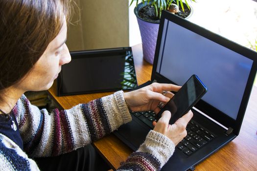 Woman working in office with digital tablet and notebook, writing and typing on the device