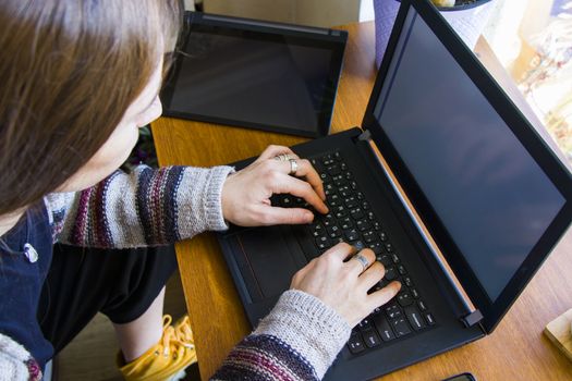 Woman working with notebook in workplace, digital tablet, mobile phone, coffee and plants in workspace, home working