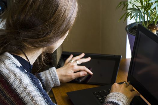 Woman working with notebook in workplace, digital tablet, mobile phone, coffee and plants in workspace, home working