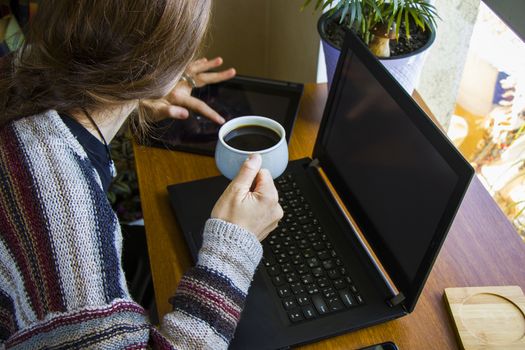 Woman working with notebook in workplace, digital tablet, mobile phone, coffee and plants in workspace, home working