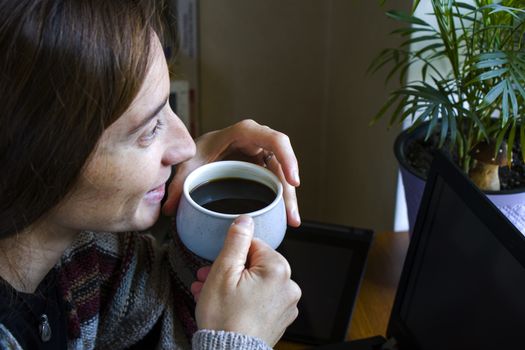 Woman working with notebook in workplace, digital tablet, mobile phone, coffee and plants in workspace, home working