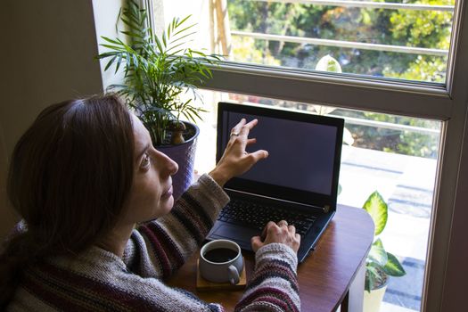 Woman working in office with digital tablet and notebook, writing and typing on the device