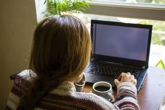 Woman working with notebook in workplace, digital tablet, mobile phone, coffee and plants in workspace, home working