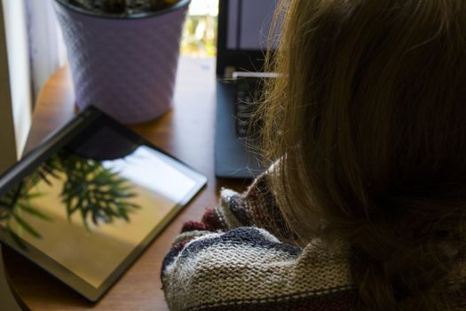 Woman working in office with digital tablet and notebook, writing and typing on the device