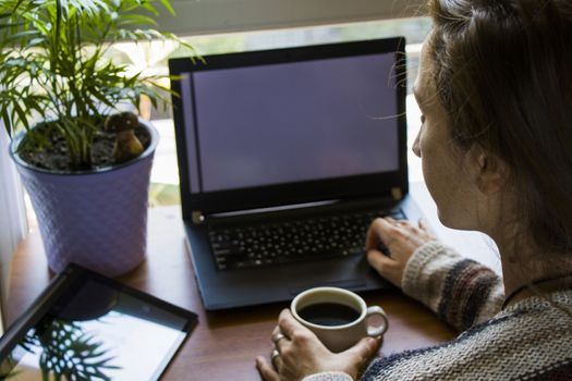 Woman working with notebook in workplace, digital tablet, mobile phone, coffee and plants in workspace, home working