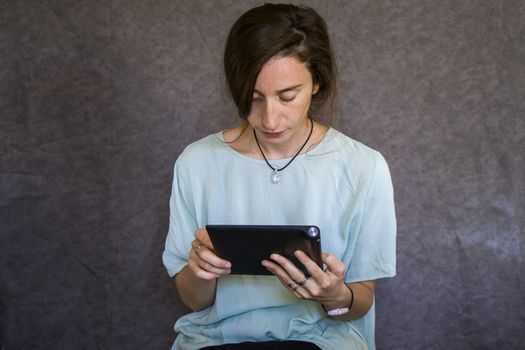 Woman worker with digital tablet in hands on the gray background, studio shoot