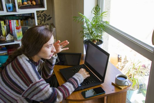 Tbilisi, Georgia - October 09, 2020: Woman working with notebook in workplace, digital tablet, mobile phone, coffee and plants in workspace, home working