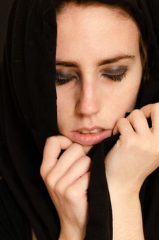 Portrait photograph of a Caucasian girl with closed eyes covered with a black sheet