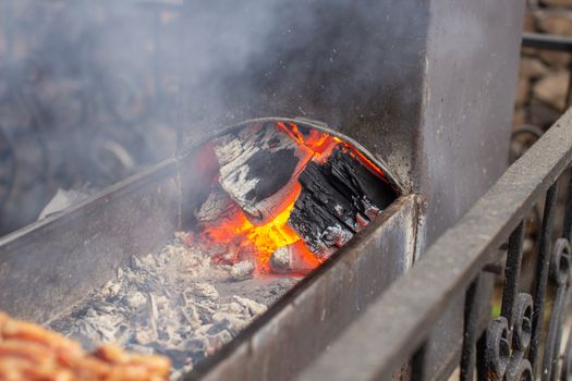 We cook a lot of kebabs on the grill. The burning coals. Kebabs strung on wooden skewers in a street cafe. The process of cooking kebabs with a lot of smoke.