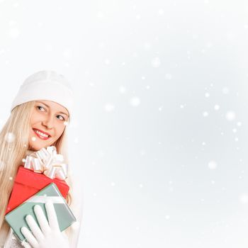 Happy woman holding Christmas gifts, silver background and snow glitter with copyspace, shopping and holidays