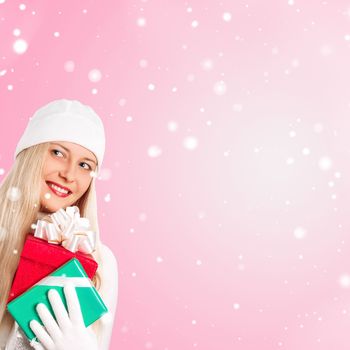 Happy woman holding Christmas gifts, pink background and snow glitter with copyspace, shopping and holidays